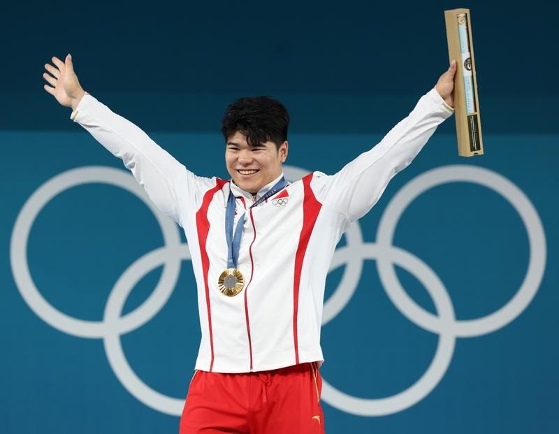 举重比赛中国队选手拼尽全力，捧得冠军奖杯